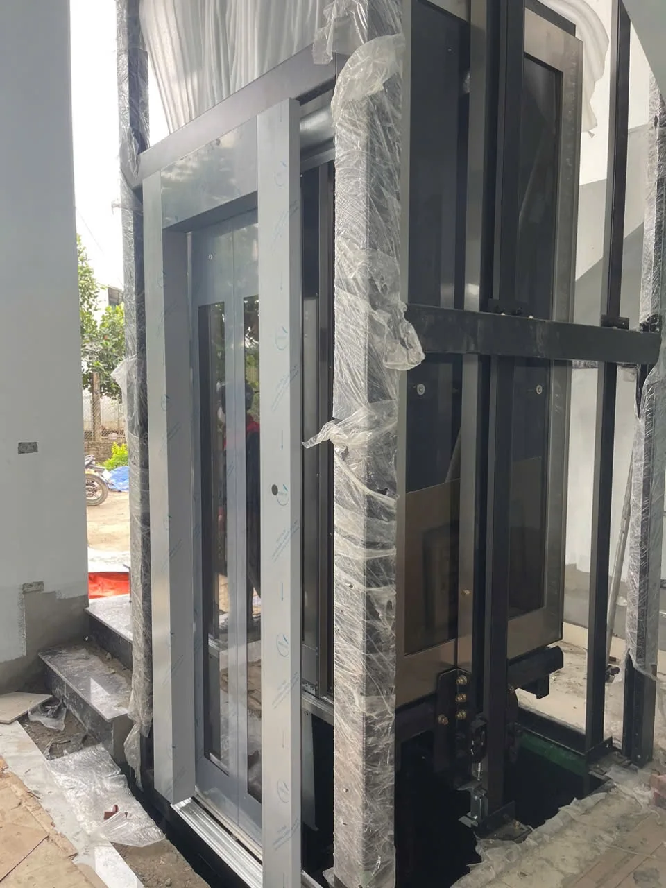 Khung giếng thang và cửa đang lắp, một số cột còn bọc vật liệu bảo vệ.