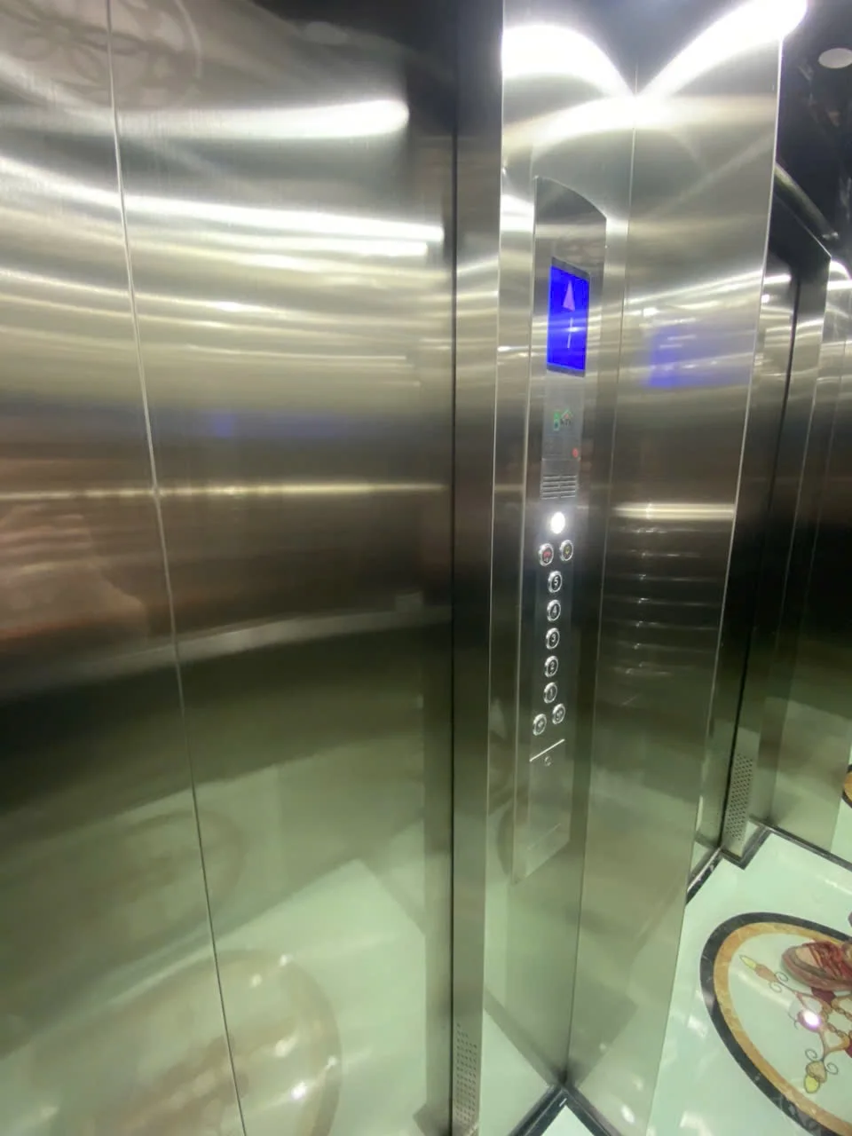 Dãy nút điều khiển và màn hình xanh trên vách inox của cabin.