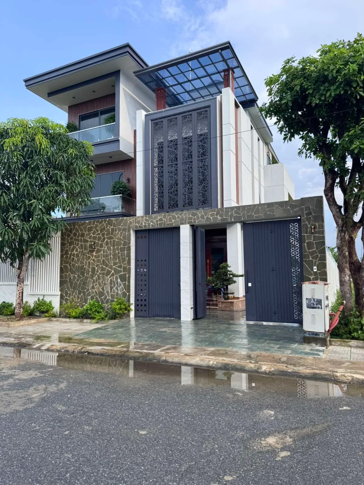Mặt tiền nhà hoàn thiện với cửa cổng tối và giàn mái phía trên.