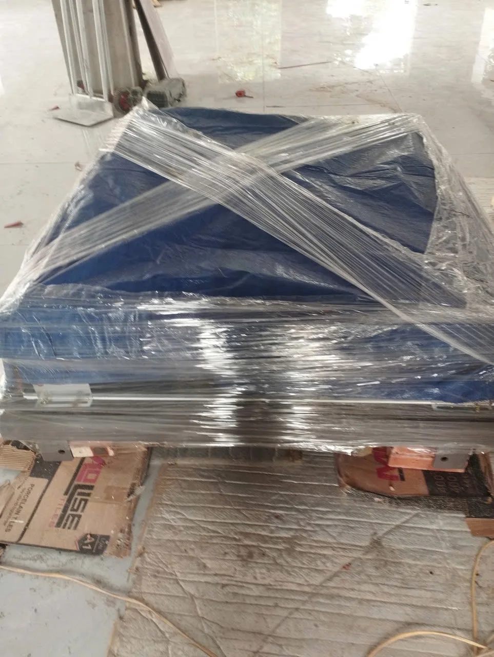 Kiện thiết bị được phủ màu xanh và quấn màng trong nhà.