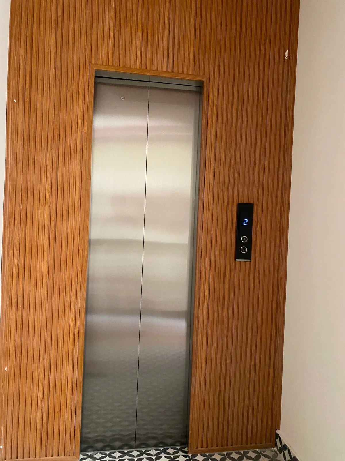 Cửa thang inox đóng, xung quanh ốp gỗ nan dọc.