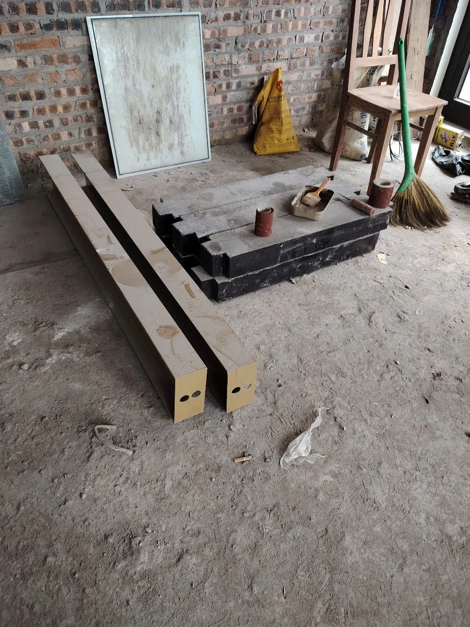 Thanh kim loại và các khối vật tư được tập kết trong không gian nhà xây thô.