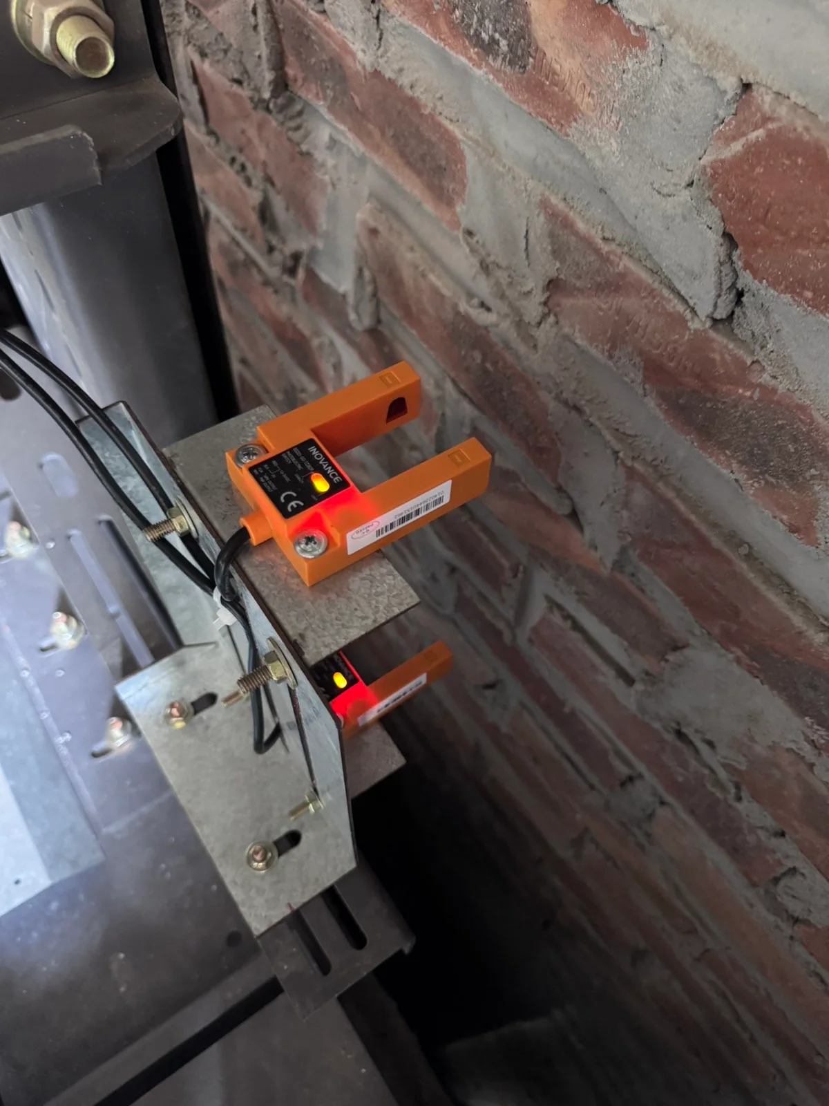 Các thiết bị màu cam có dây được lắp gần ray và tường gạch.
