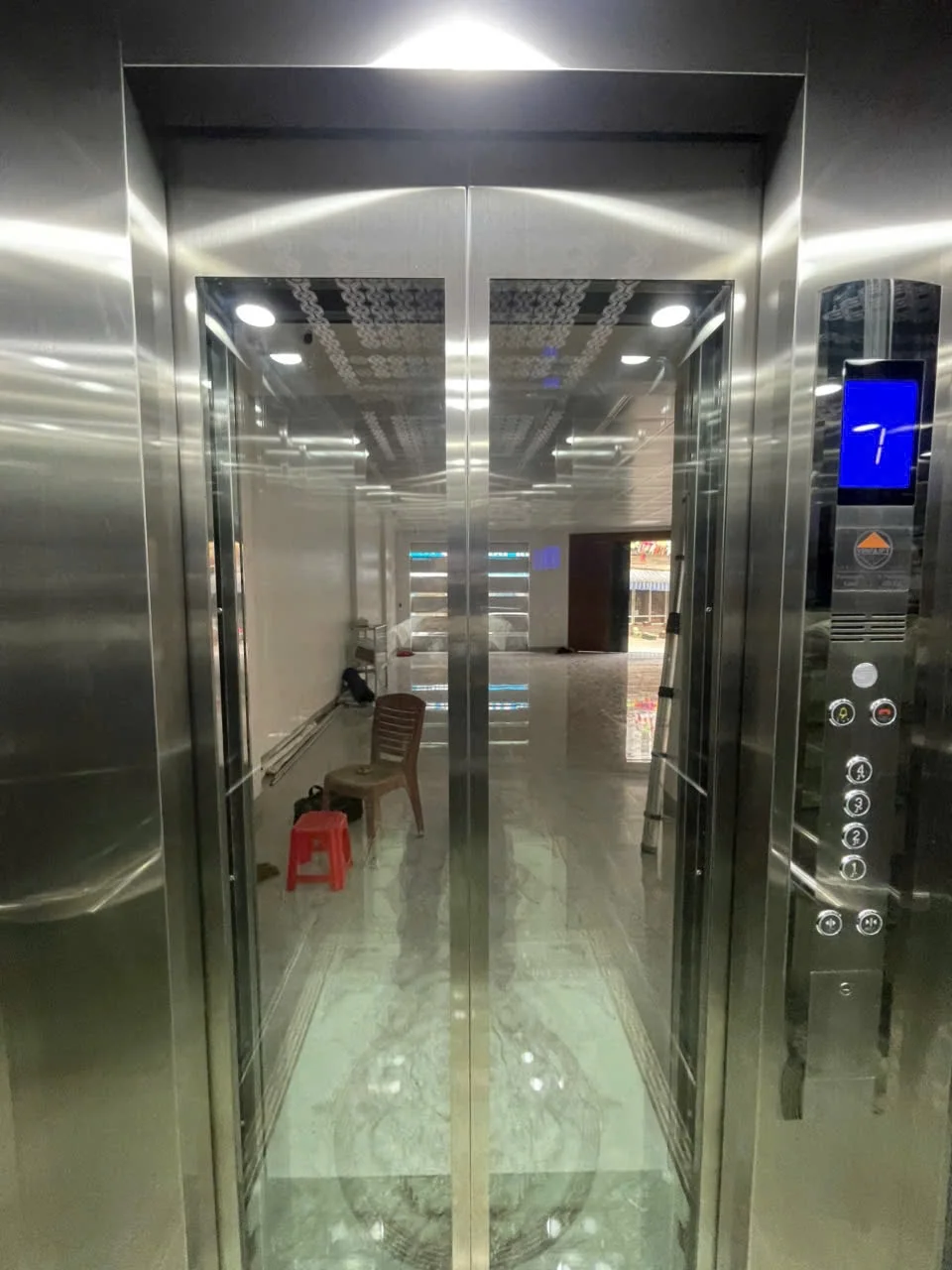 Nội thất cabin inox nhìn ra cửa kính, bảng điều khiển bên phải.